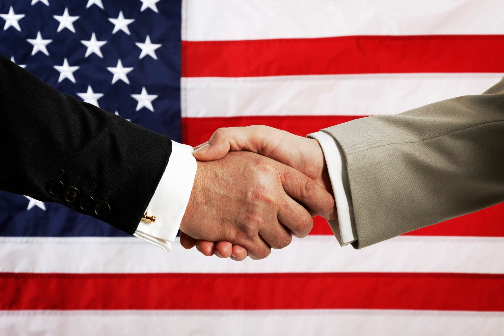 Handshake in front of U.S. flag.
