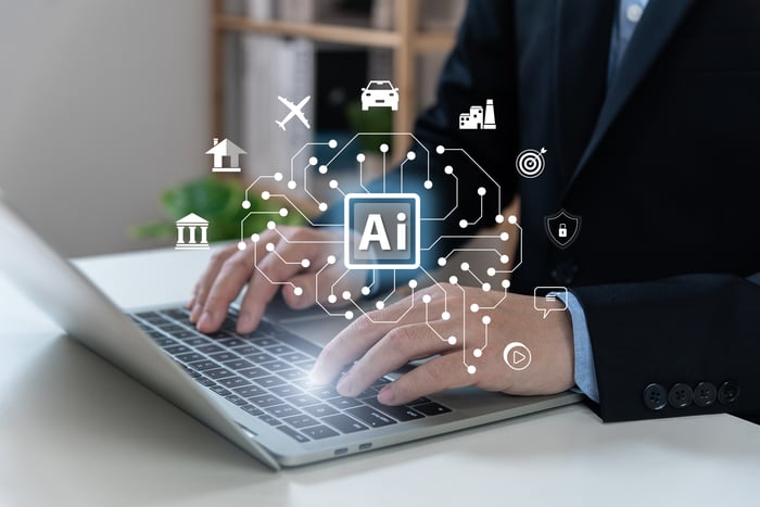 Hands typing on laptop with AI above them.