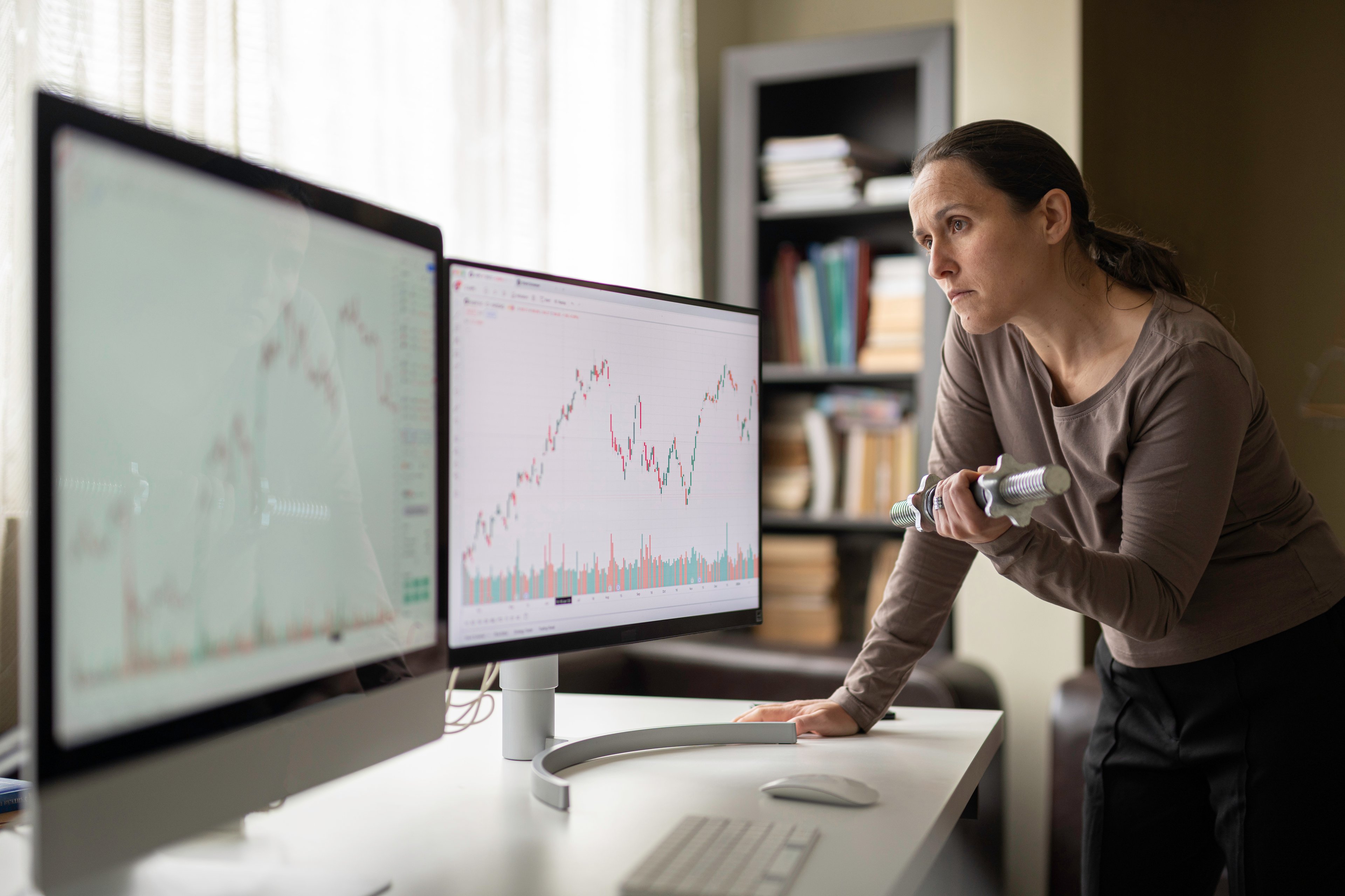 Worried-looking person examining charts on computer screens.
