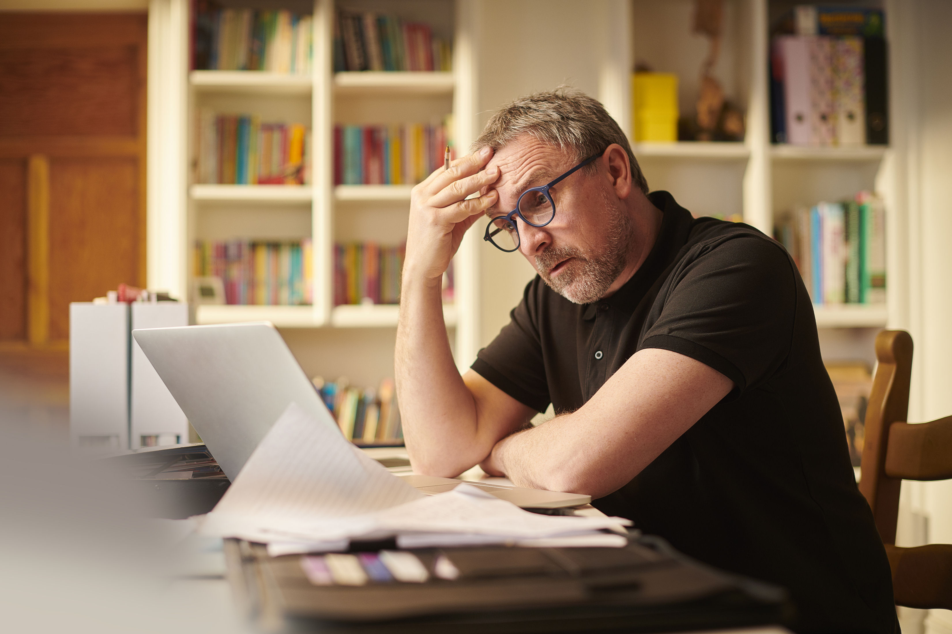 A worried retiree sitting down in front of a laptop.