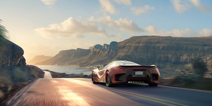 Sports car driving on road near mountains.