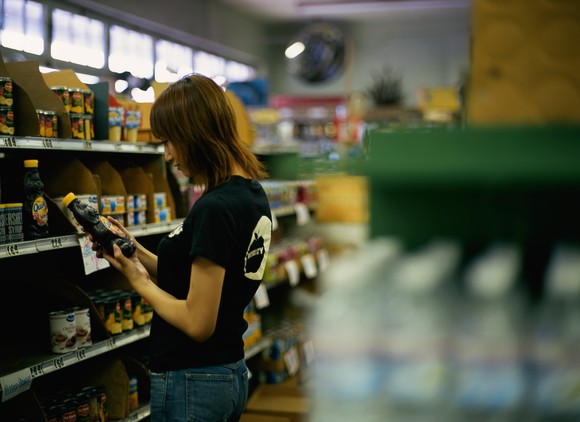 Person examines product on grocery shelf. 