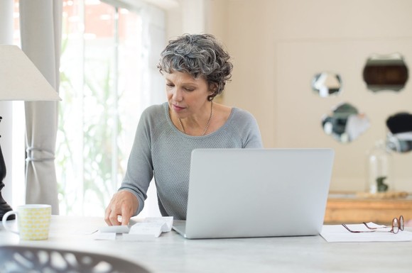 A person works at a desk with a laptop and cup of coffee.