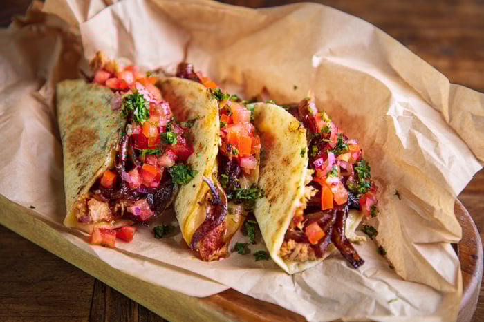 Three tacos on a piece of parchment paper.