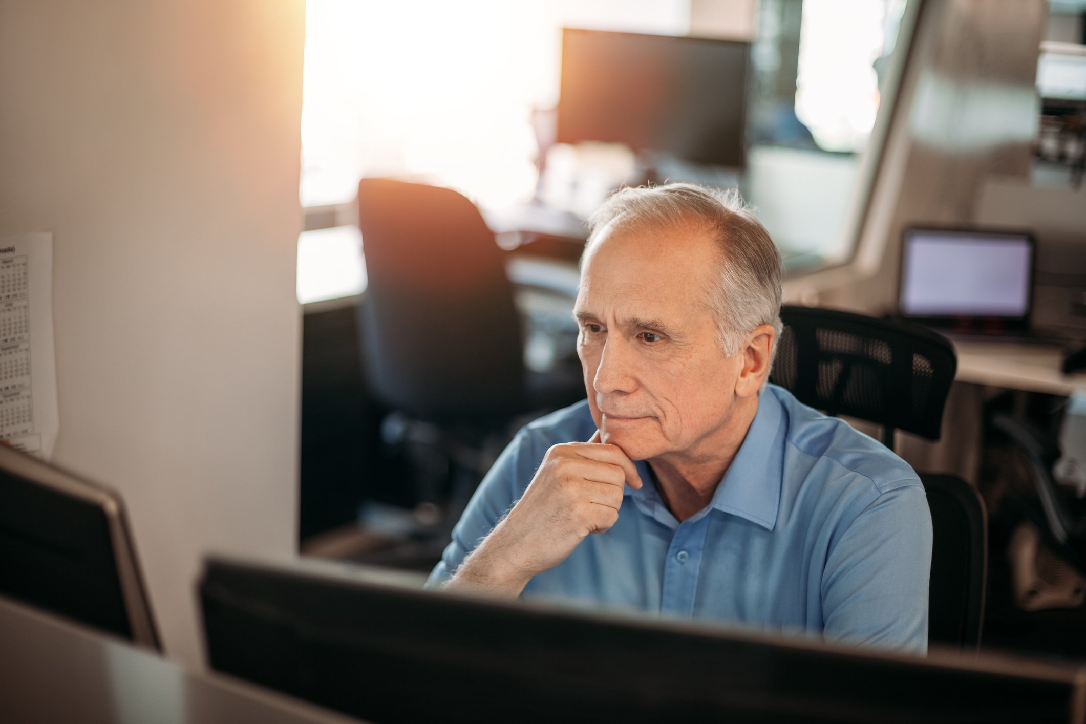 Older man serious expression at computer