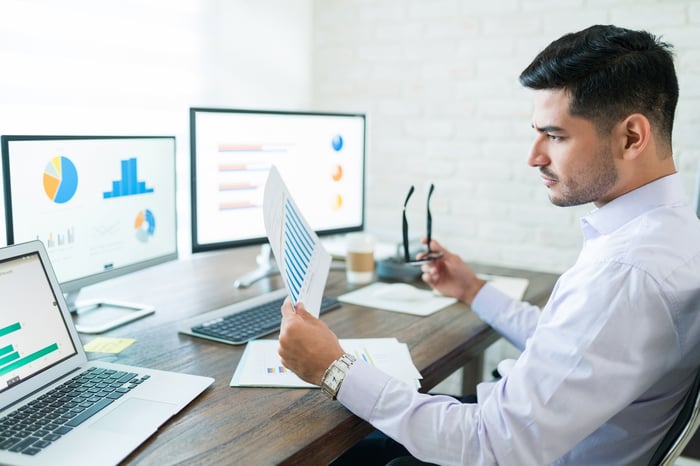 An analyst looking at charts on a computer.