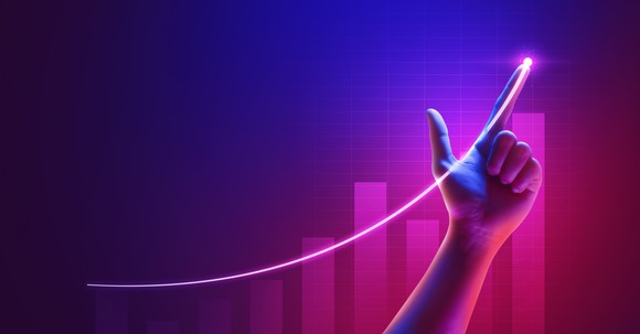 A person pointing at a line tracking a bar chart going up.