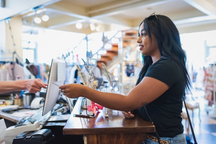 A woman paying for something at a store with a credit card. 