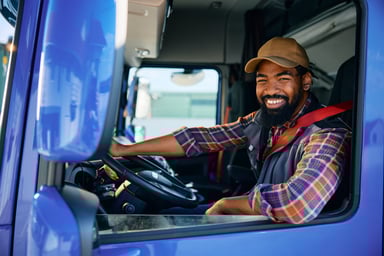 Smiling person in the drivers seat of a truck