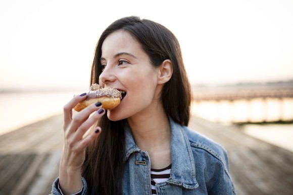 Woman taking a bite of a pastry. 