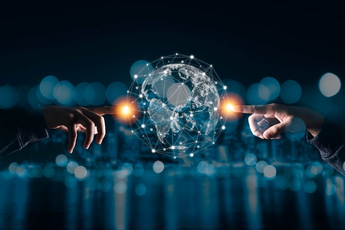 Two hands pointing toward a glowing digital globe with connected network lines and nodes.
