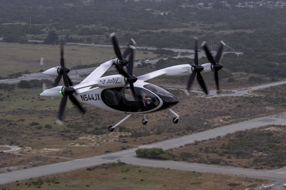 Side view of Joby Aviation eVTOL flying over a runway. 