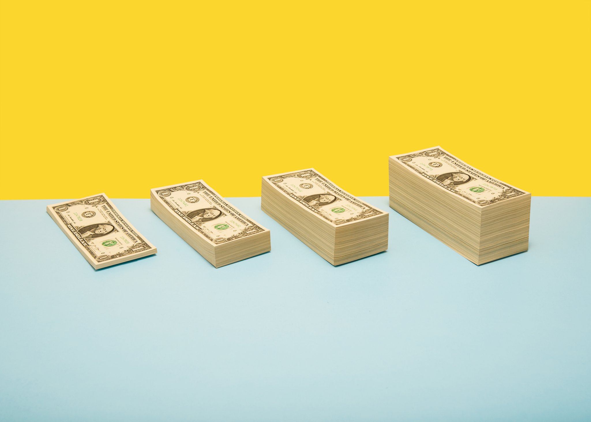 Four stacks of dollar bills increasing in size.