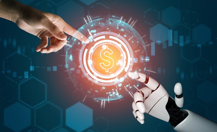 A human finger it reaching out to touch a robot finger, with a dollar sign between them.