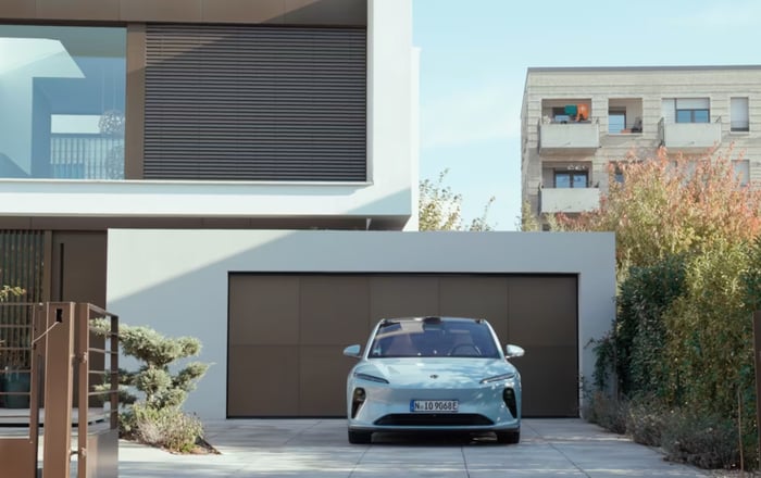 Nio EV parked in the driveway of a modern home. 
