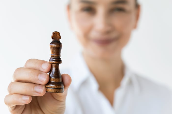 A smiling person holding a king chess piece.