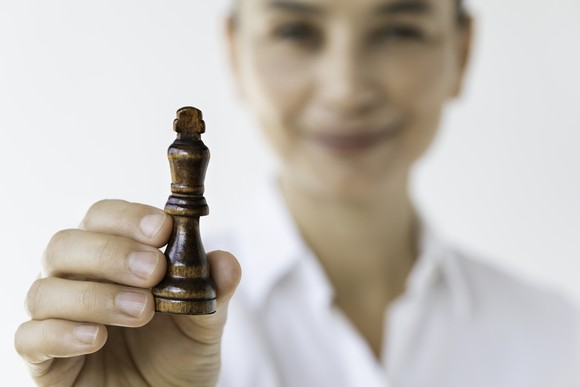 A smiling person holding a king chess piece.
