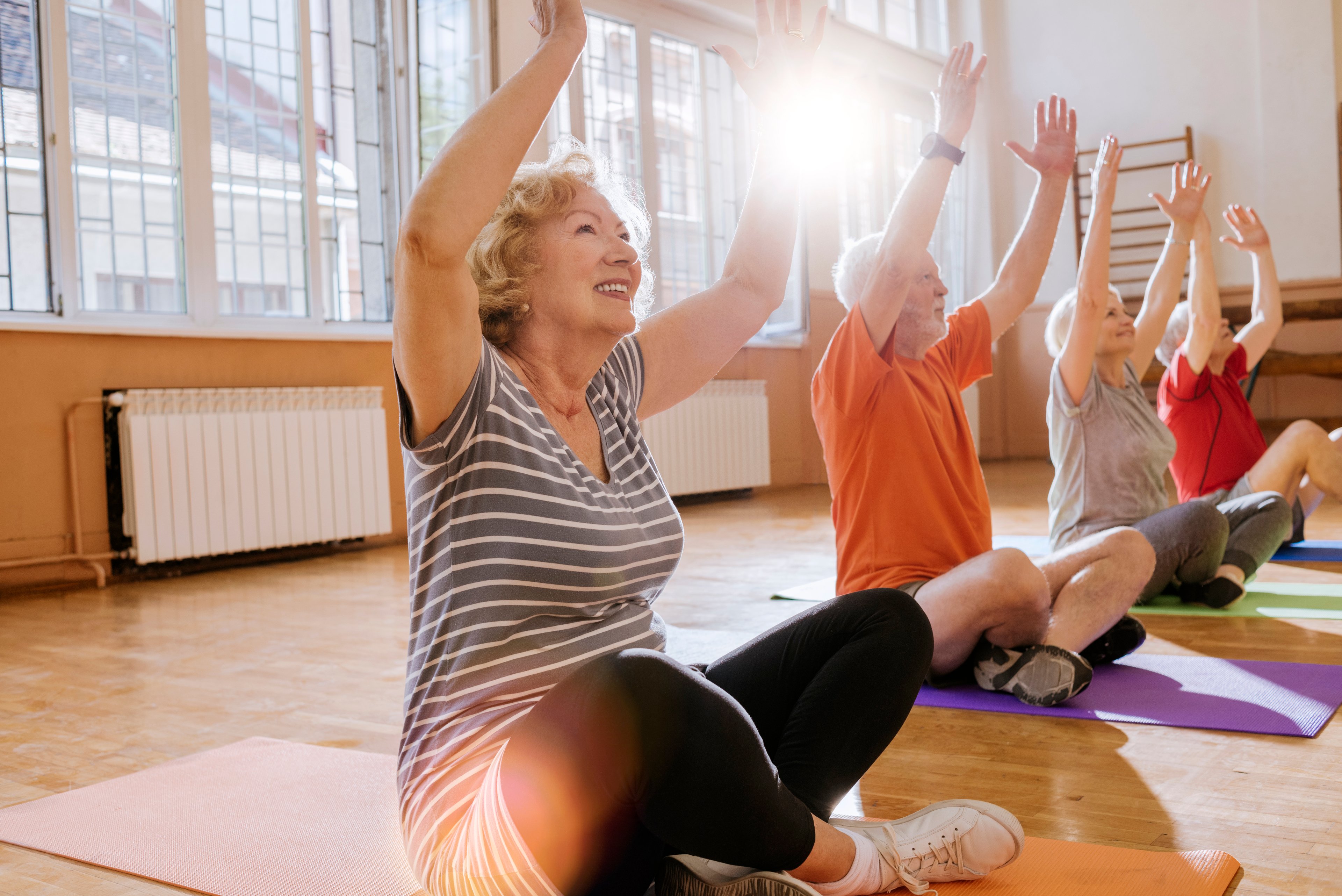 Four people sitting on mats doing yoga poses.