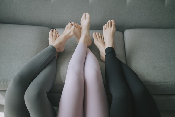 Three people display athletic-wear on a sofa.
