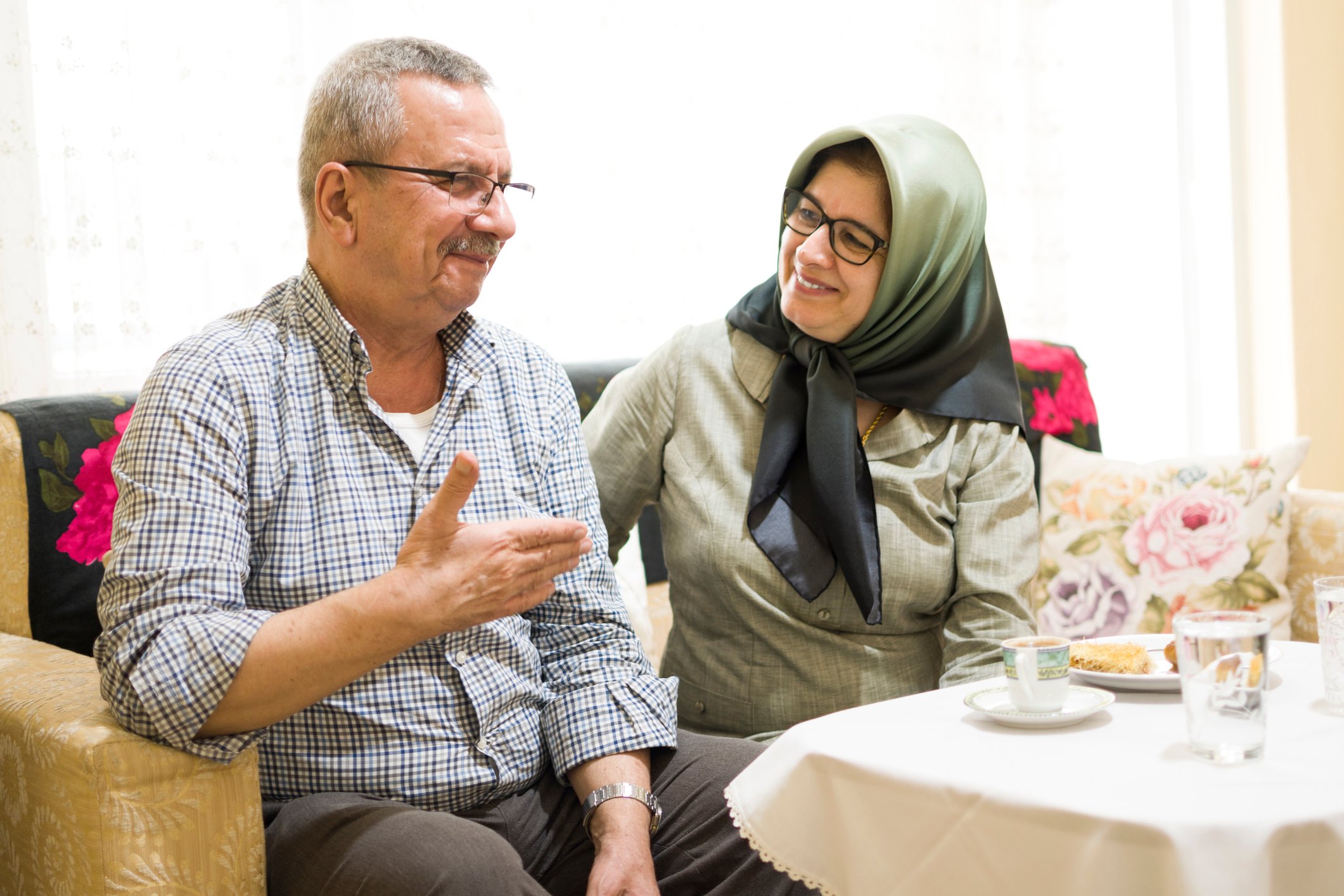 A couple is smiling, sitting on a couch.