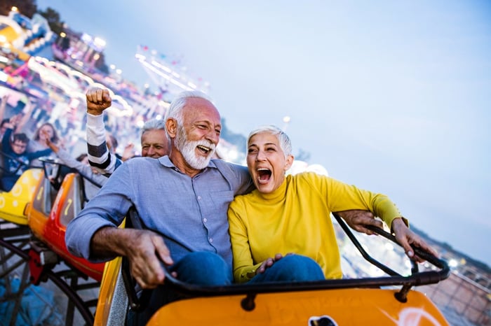 Older man and woman laughing as they ride a roller coaster. 