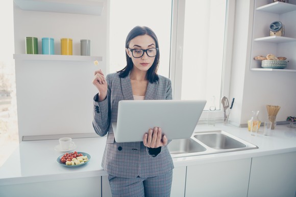 A person looks at a laptop in a kitchen.