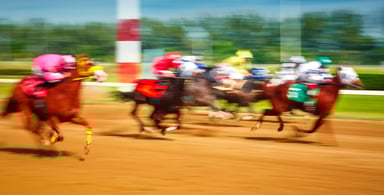 Blurred photo of racing horses in a horse race.