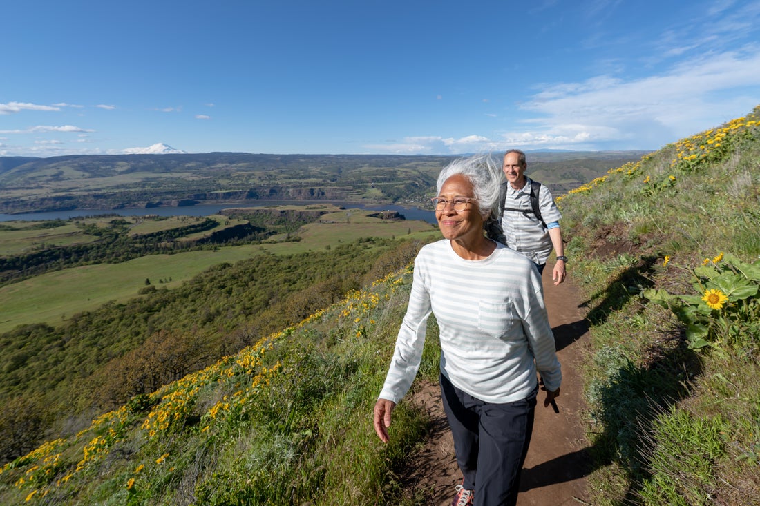 A smiling couple, hiking on a beautiful hillside. 