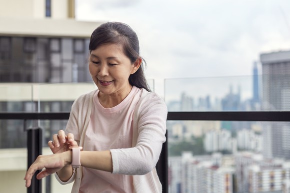 Person looking at a smartwatch while pausing in an outdoor city setting. 