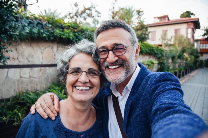 A couple in blue is outdoors and smiling broadly.