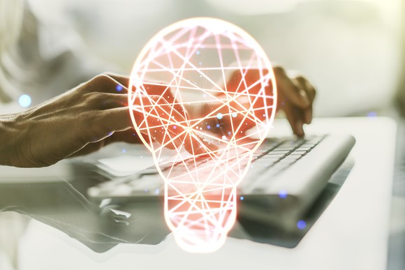Computer keyboard with a digital light bulb in front of it.