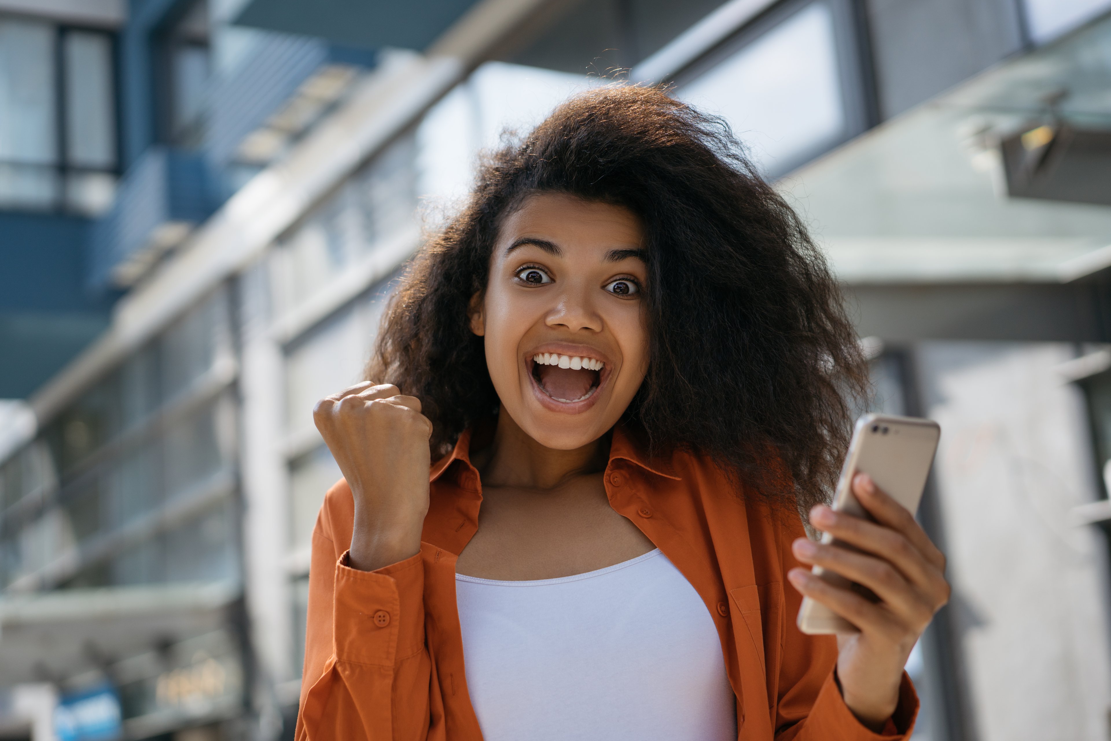 A happy person cheers while looking at a phone.