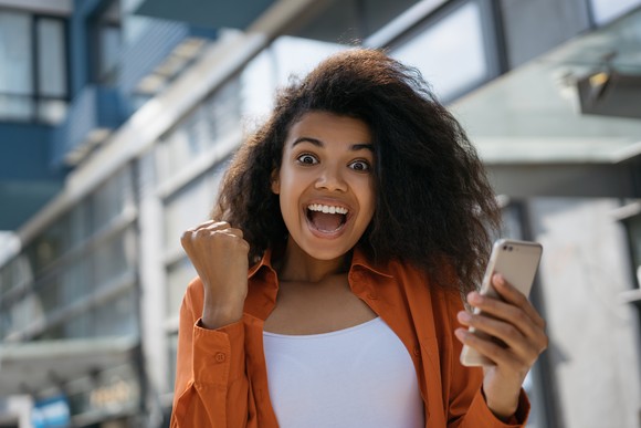 A happy person cheers while looking at a phone.