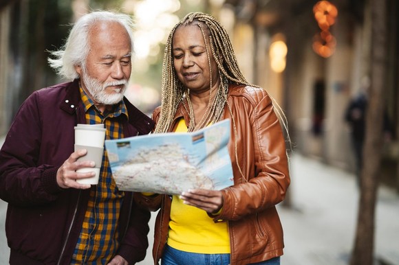 Older couple on city street, studying a paper map. 