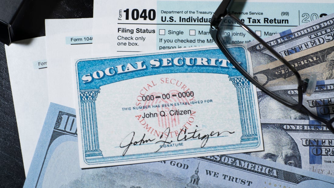 A 1040 Individual Tax Form with cash and a Social Security card lying on top. 