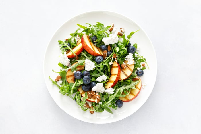 A salad with fruits, cheese, and greens.