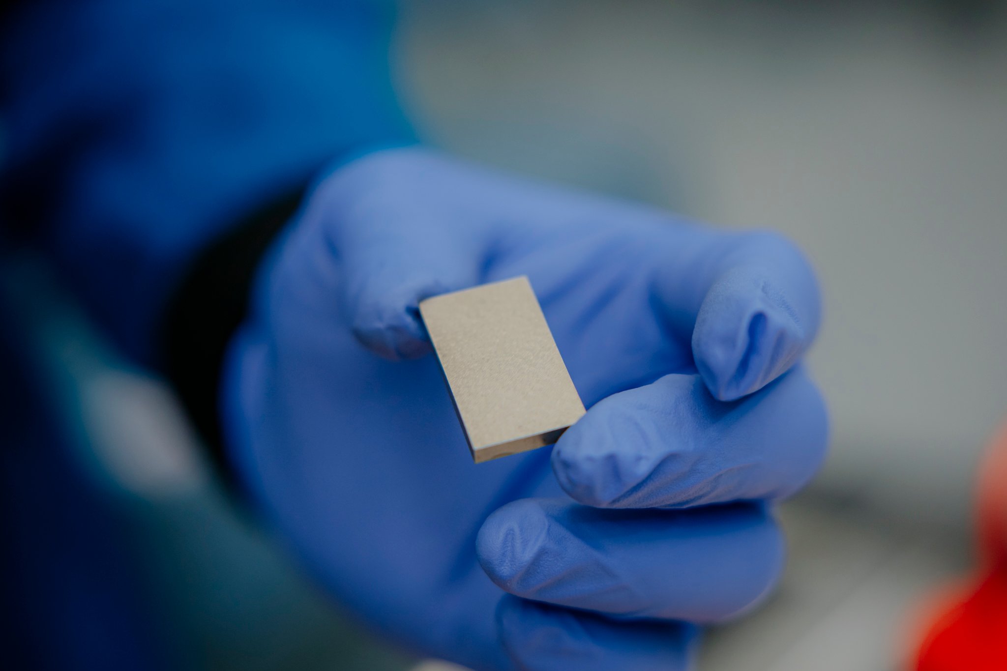A gloved hand holding a rare earth magnet at MP Materials' Independence facility in Fort Worth, Texas.