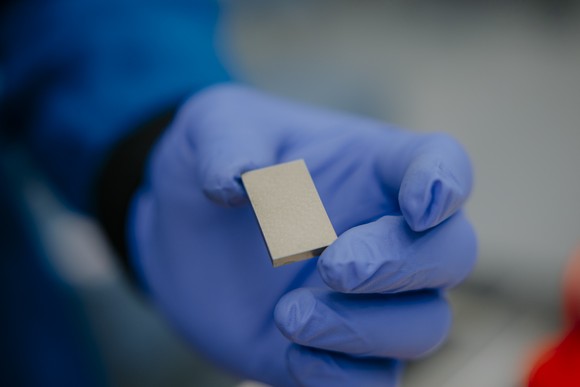 A gloved hand holding a rare earth magnet at MP Materials' Independence facility in Fort Worth, Texas.