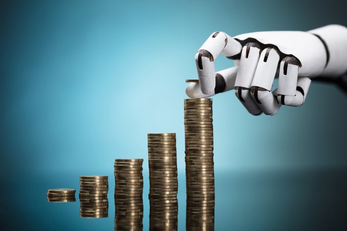 A white robot hand stacks coins in rising piles.
