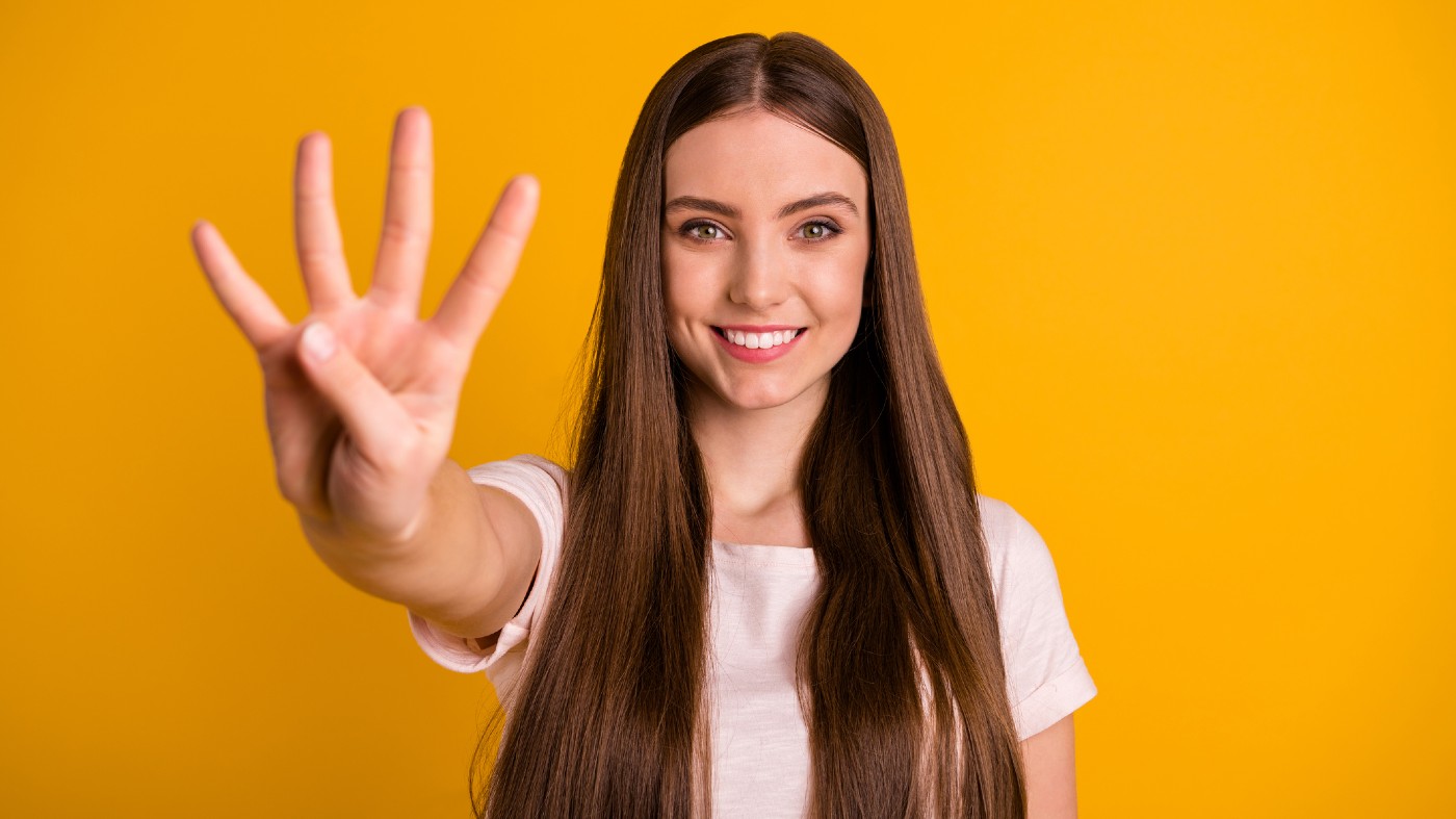 Person smiling and holding up four fingers.