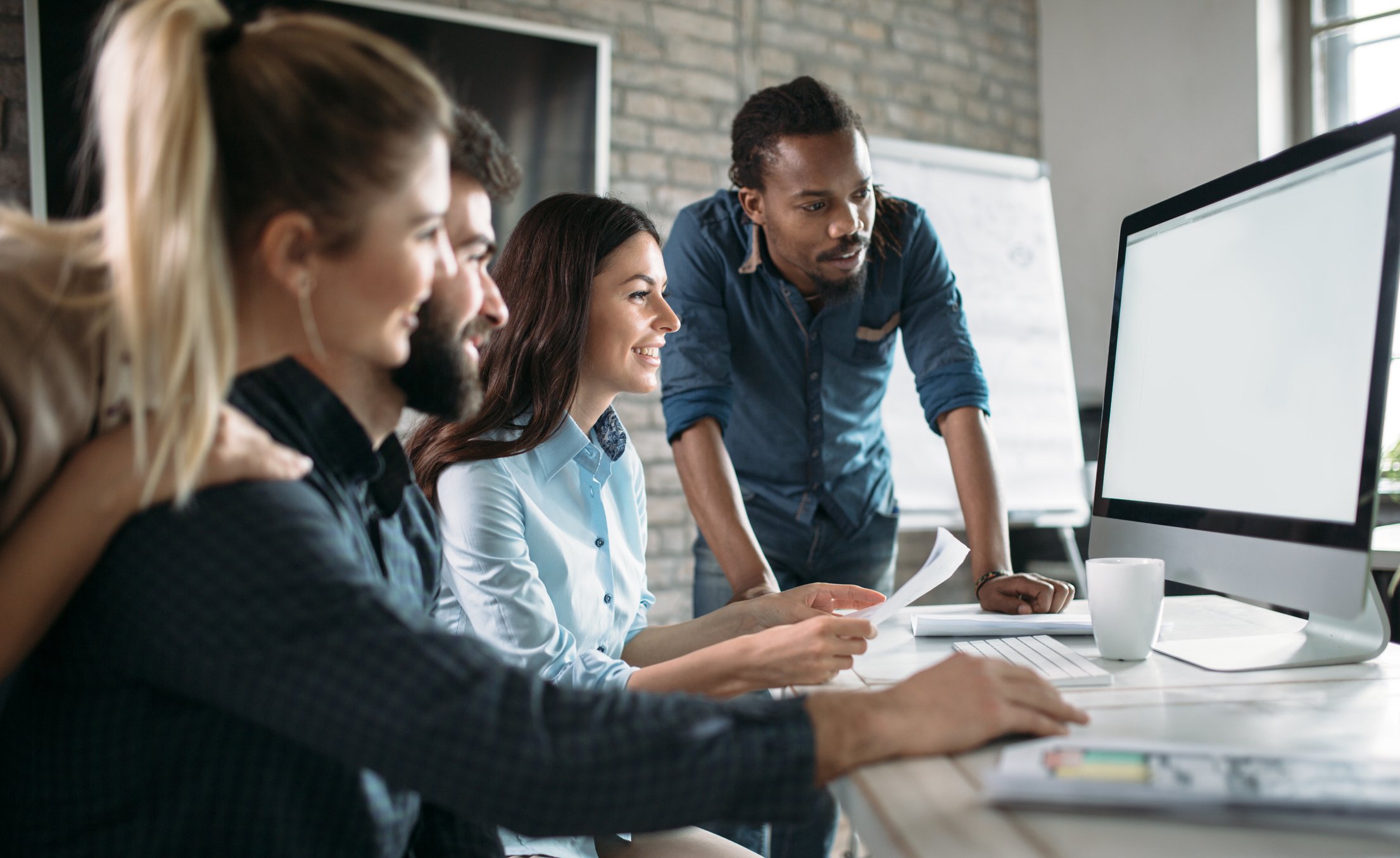 A group of young investors looks at something on a computer.