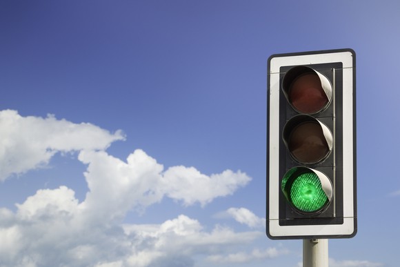 Green stoplight against blue skies.