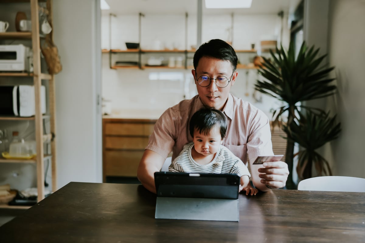 A parent sitting with a baby on their lap in front of a computer.