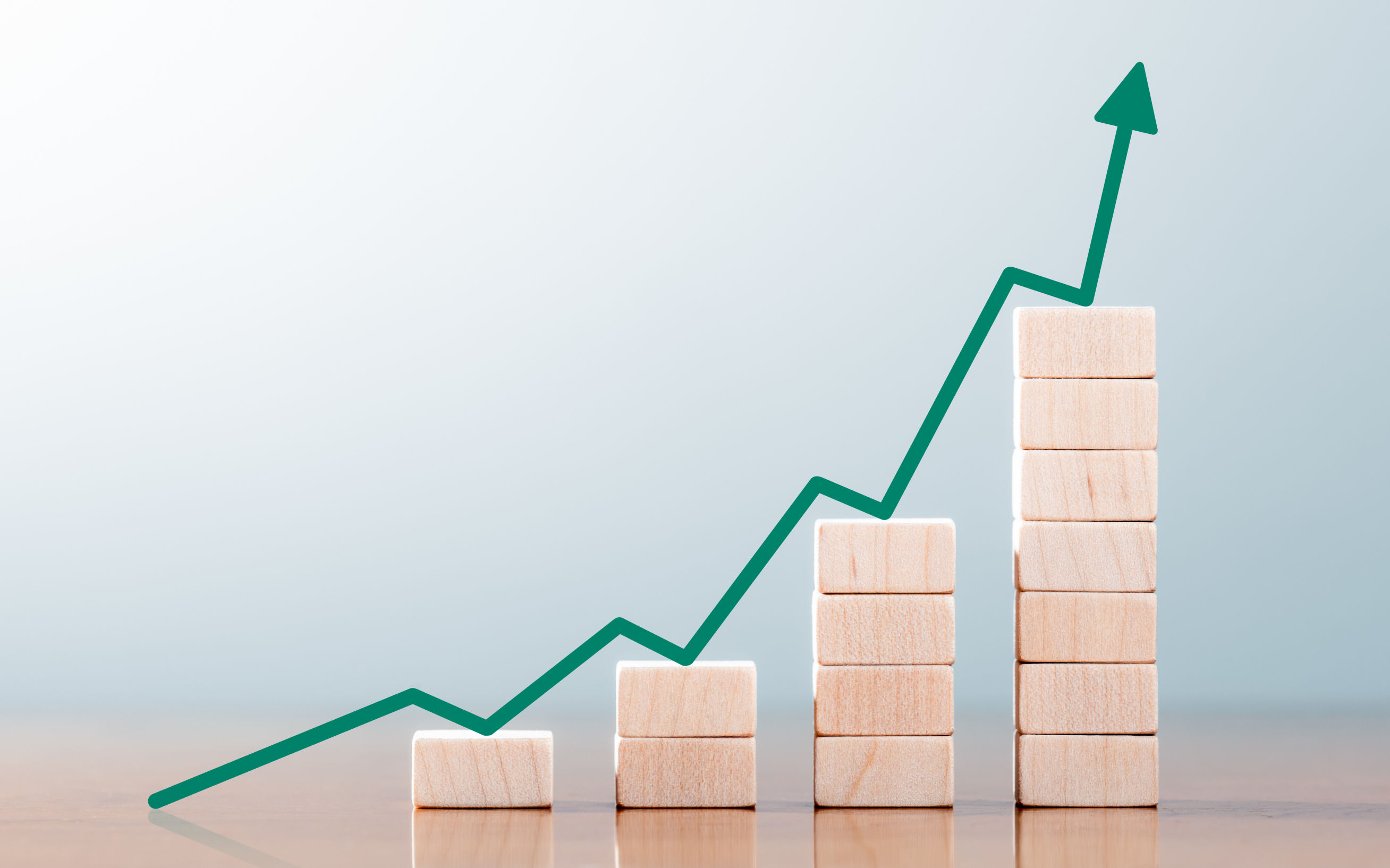 Rising bar chart made of wooden blocks showing accelerating growth.