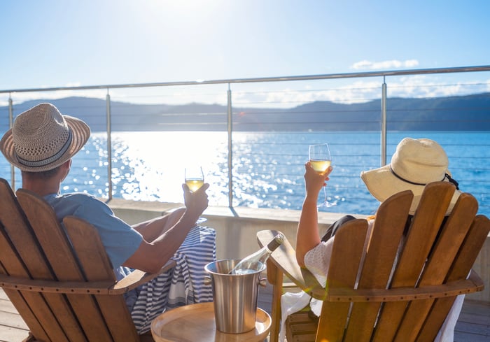 Two people raise wine glasses on the deck of a cruise ship. 