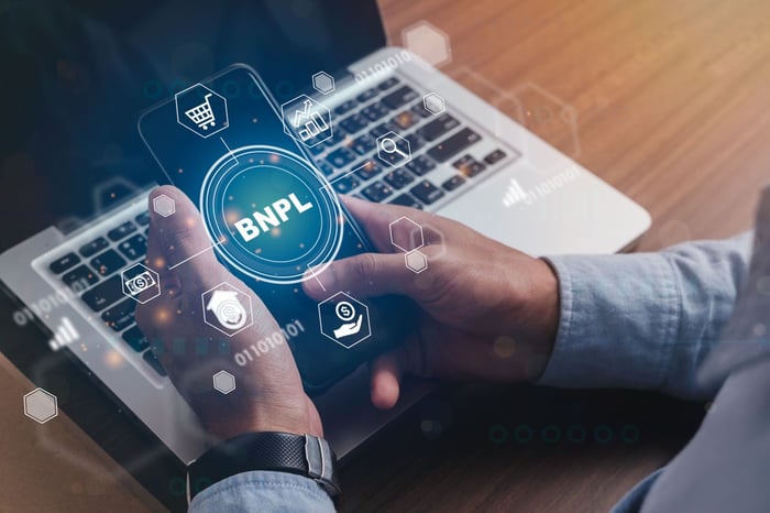 Someone holding a cell phone with the letters "BNPL" lit up. 