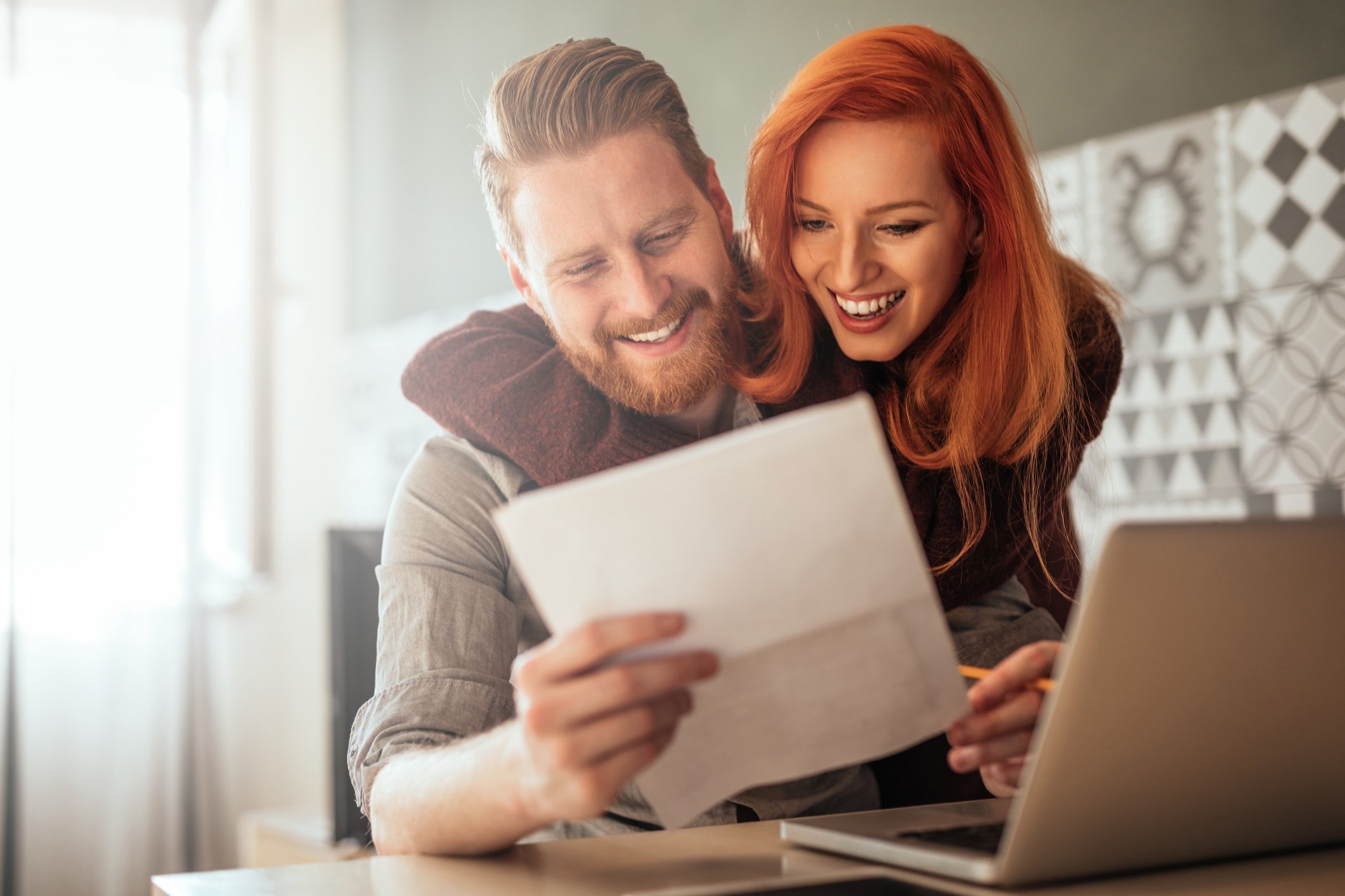 Two investors look at a document in front of a laptop.