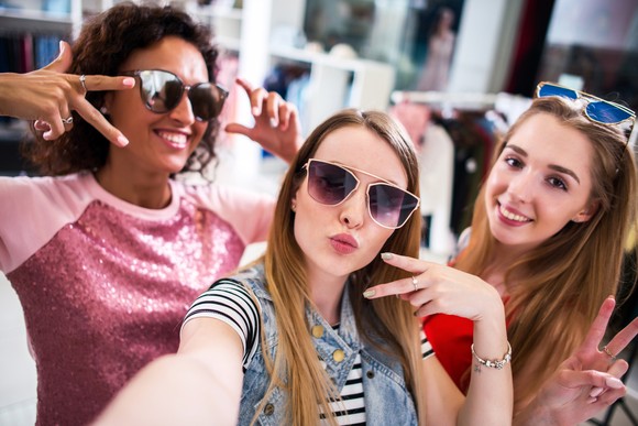 Three young shoppers take a selfie in a store.