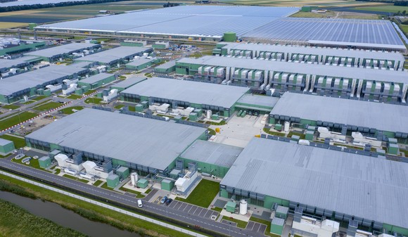 aerial view of data center campus with adjacent solar panel field powering it. 