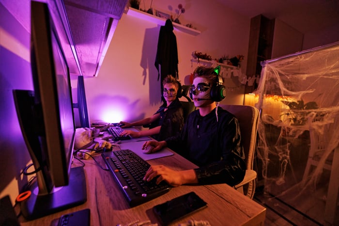 Two young people in costume using PCs.